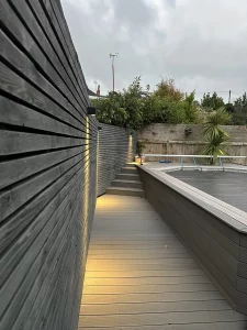 lluminated walkway beside a pool in a landscaped garden.