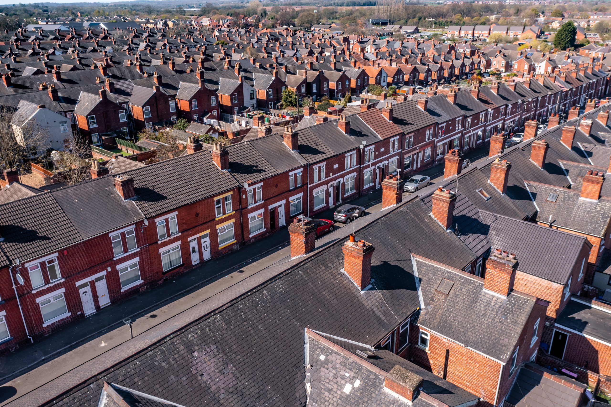 Aerial view above rows of back to back terraced houses on a large council estate